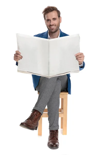 Positiver lässiger Mann, der eine Zeitung hält und lächelt — Stockfoto