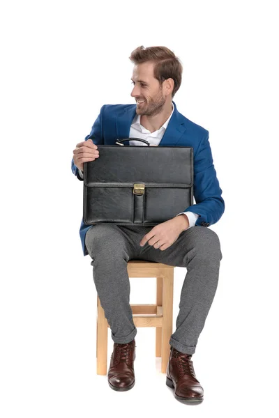 Молодой бизнесмен смеется и держит свой портфель — стоковое фото