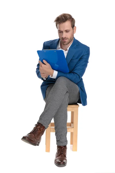 Fokussierter lässiger Kerl liest aus seinem Klemmbrett — Stockfoto