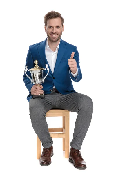 Hombre casual dando un pulgar hacia arriba y sosteniendo su trofeo — Foto de Stock