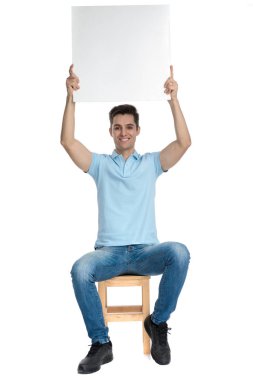 Başının üstünde boş bir reklam tutan mutlu rahat adam 