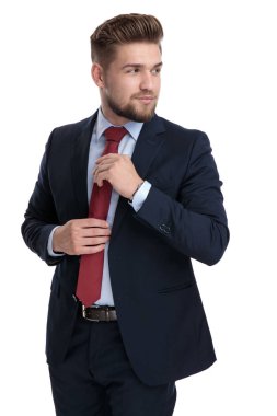 Meraklı işadamı kravatını düzeltiyor ve omzunun üzerinden bakıyor