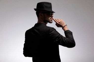 Gizemli bir rahat adam sessizlik gesturing geri görünümü 