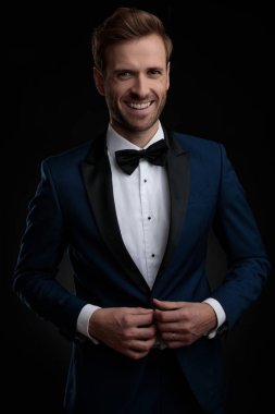 Neşeli genç adam onun mavi smokin ayarlama ve gülüyor