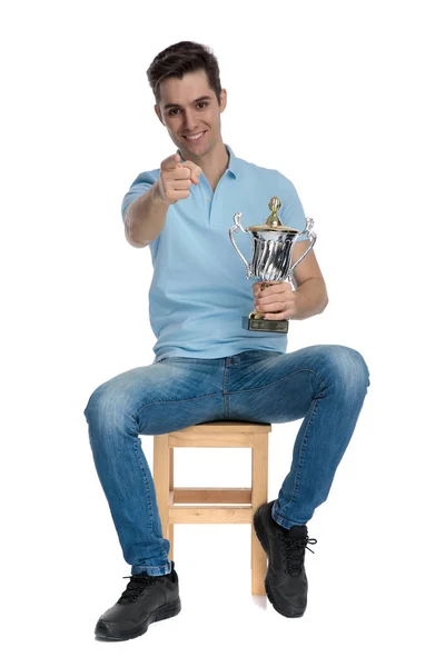 自信的休闲男人指着并拿着奖杯 — 图库照片