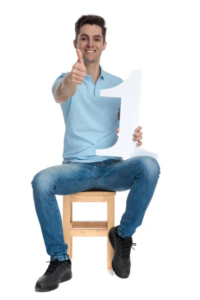 Hombre dando un pulgar hacia arriba y sosteniendo un número uno —  Fotos de Stock