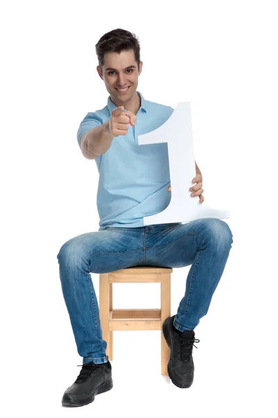 Positiver lässiger Typ, der eine Nummer eins zeigt und hält — Stockfoto