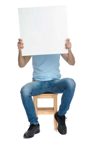 Casual homem cobrindo seu rosto com um cartaz vazio — Fotografia de Stock