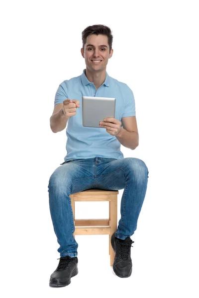 Joyful casual man pekar och håller en tablett — Stockfoto