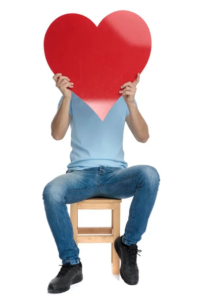 Hombre casual cubriendo su cara con una forma de corazón — Foto de Stock