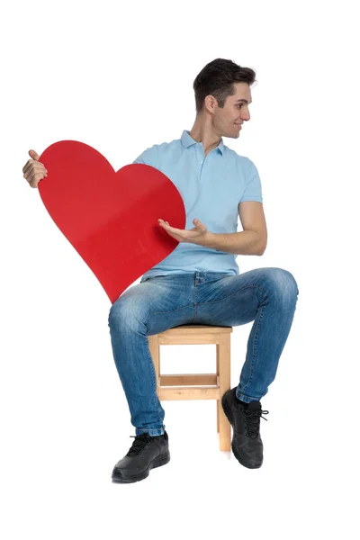 Schöner lässiger Typ, der eine rote Herzform präsentiert — Stockfoto