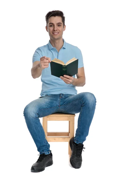 Handsome casual man pointing and holding a book — Stock Photo, Image