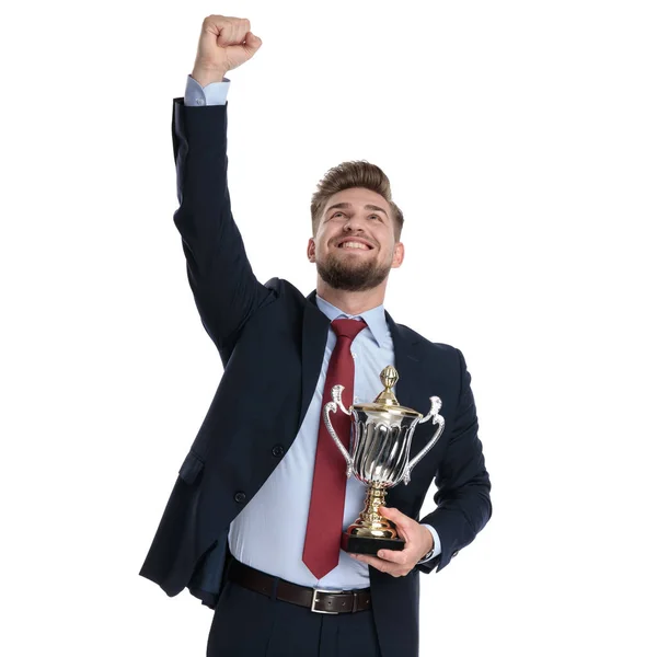 Hoppfull affärsman som håller en trofé och firar — Stockfoto