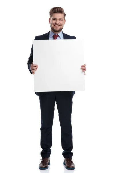 Hombre de negocios confiado sonriendo y sosteniendo una cartelera en blanco — Foto de Stock