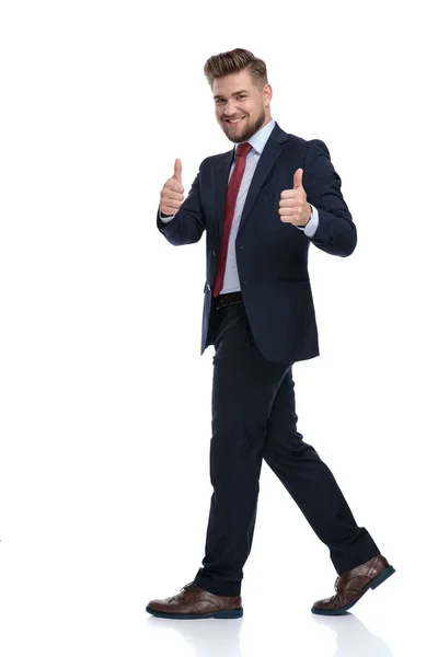 カジュアルなビジネスマンが歩いて、二重の親指を与える — ストック写真