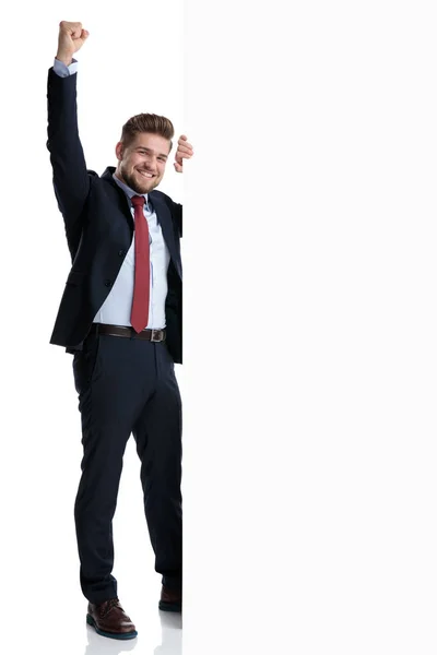 Empresario celebrando junto a una valla publicitaria en blanco — Foto de Stock