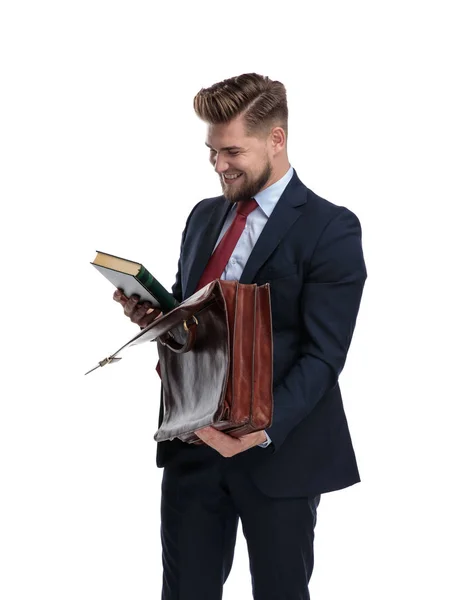 Businessman laughing while reading a book and holding his briefc — Stock Photo, Image