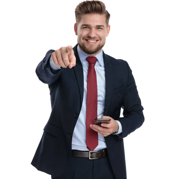 Cheerful businessman pointing and holding his phone — Stock Photo, Image