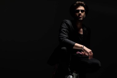 Güneş gözlüğü, siyah ceket ve şapka takan sert dramatik adam