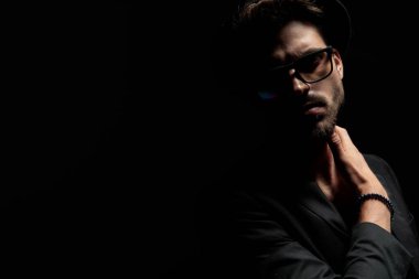 Yakışıklı dramatik adam boynuna dokunuyor ve ileriye bakıyor