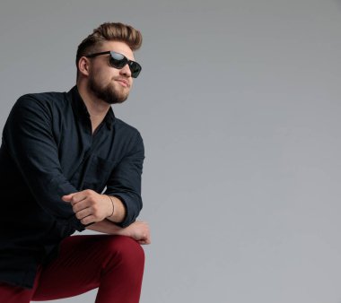 Umutlu rahat adam bacağına yaslanmış ve uzağa bakıyor 