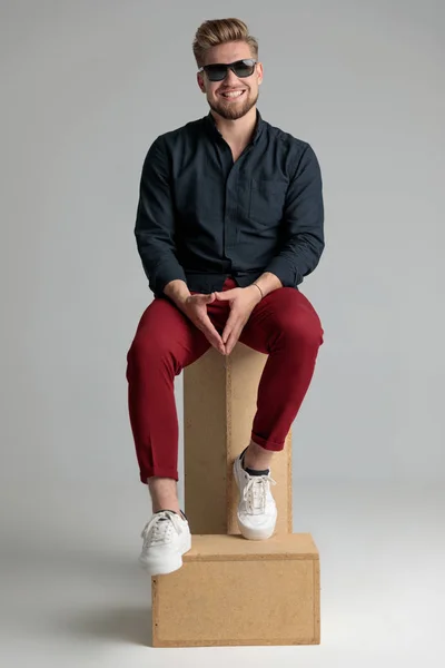 Alegre hombre casual riendo en un trono hecho de cajas — Foto de Stock