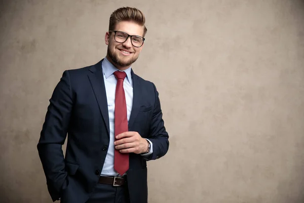 Empresário feliz ajustando sua gravata e sorrindo — Fotografia de Stock