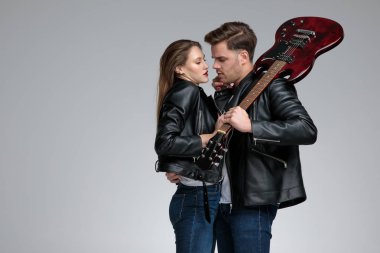 Tutkulu adam kız arkadaşı kucaklayan ve bir gitar tutarak