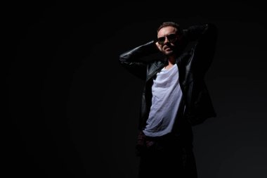 Rahat punk adam boynunun arkasında iki elini tutarak