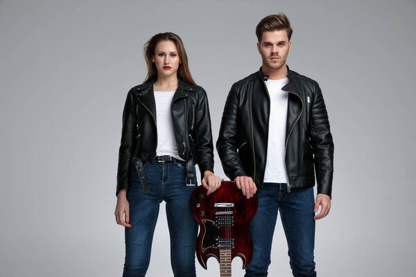 Confident rock couple leaning on an electric guitar