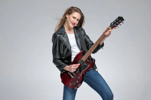 Chica joven apasionada tocando la guitarra y con un jacke de cuero — Foto de Stock