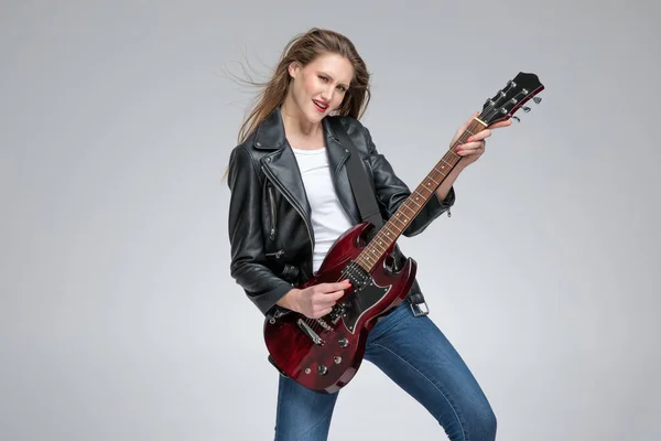 Passionate young girl playing guitar and wearing a leather jacke — Stock Photo, Image