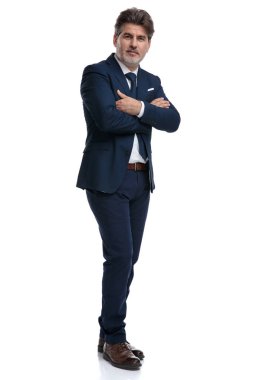 Kollarını tutan ciddi görünümlü işadamı pantolonlarını çapraz
