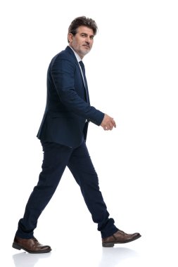 Yürüyen ve gülümseyen pozitif bir işadamının yan görünümü