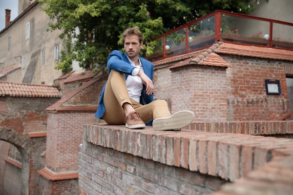 Man in smart casual clothes rests on a brick wall — Stock Photo, Image