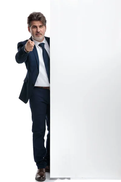 Old businessman pointing forward while standing beside an empty — Stock Photo, Image