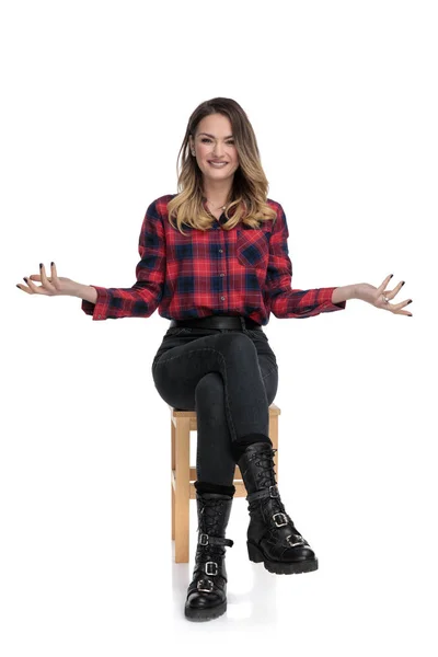 Casual vrouw in geruite shirt zit en het verhogen van de handen — Stockfoto