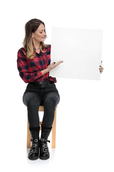 Casual kvinna sitter med blank skylt till en sida — Stockfoto