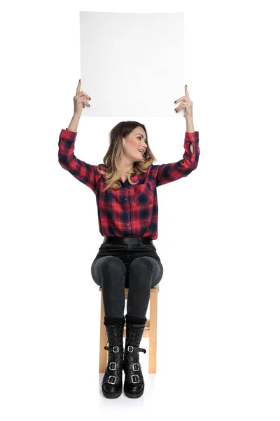 Lässige Frau sitzt mit Plakatwand über Kopf zur Seite — Stockfoto