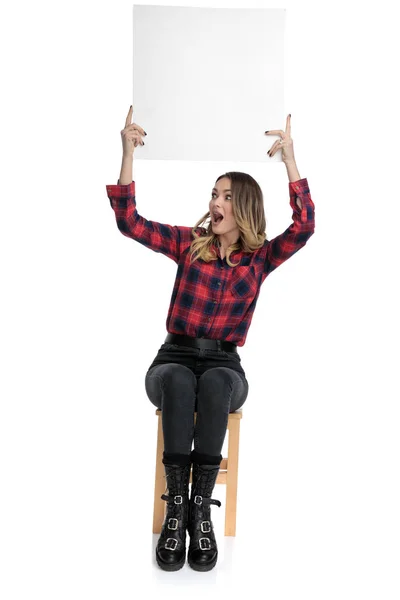 Casual Frau sitzt mit Plakatwand über Kopf zu einer Seite erstaunlich — Stockfoto