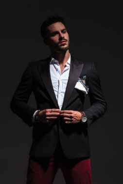 serin zarif genç adam onun takım elbise düğmeleme ve uzağa bakar 