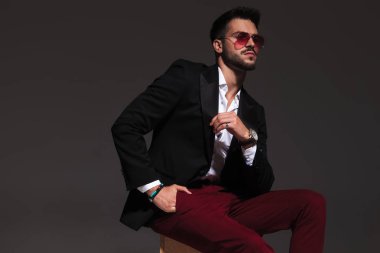 serin maço adam cebinde el ile oturur ve uzağa bakar 