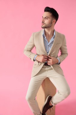 ahşap bir kutu üzerinde oturan ceket sabitleme çekici genç adam