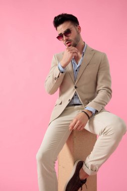 akıllı rahat adam ahşap bir kutu üzerinde oturan dudaklarına dokunarak