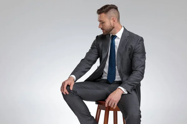 Jovem empresário sentado em um banquinho olha para longe — Fotografia de Stock