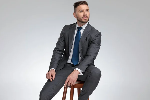 Young elegant businessmn sits on stool and dreams — Stock Photo, Image