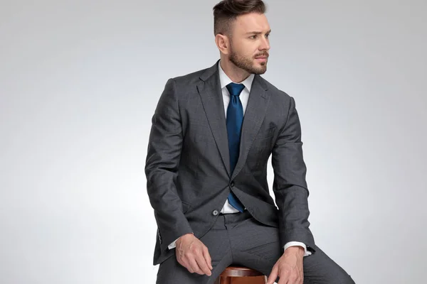 Young sexy businessman sitting on chair and looks to side — Stock Photo, Image
