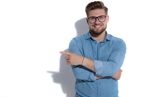 Sonriente joven casual hombre señalando el dedo a un lado — Foto de Stock