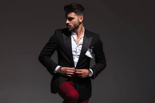 Sexy Mann knöpft seinen Smoking Mantel und schaut zur Seite — Stockfoto