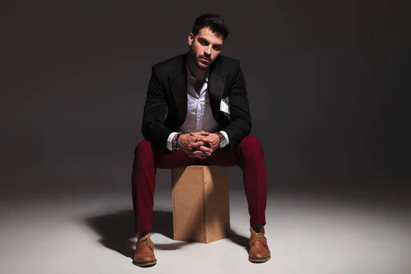 Sexy elegante homem sentado na caixa e de mãos dadas juntos — Fotografia de Stock